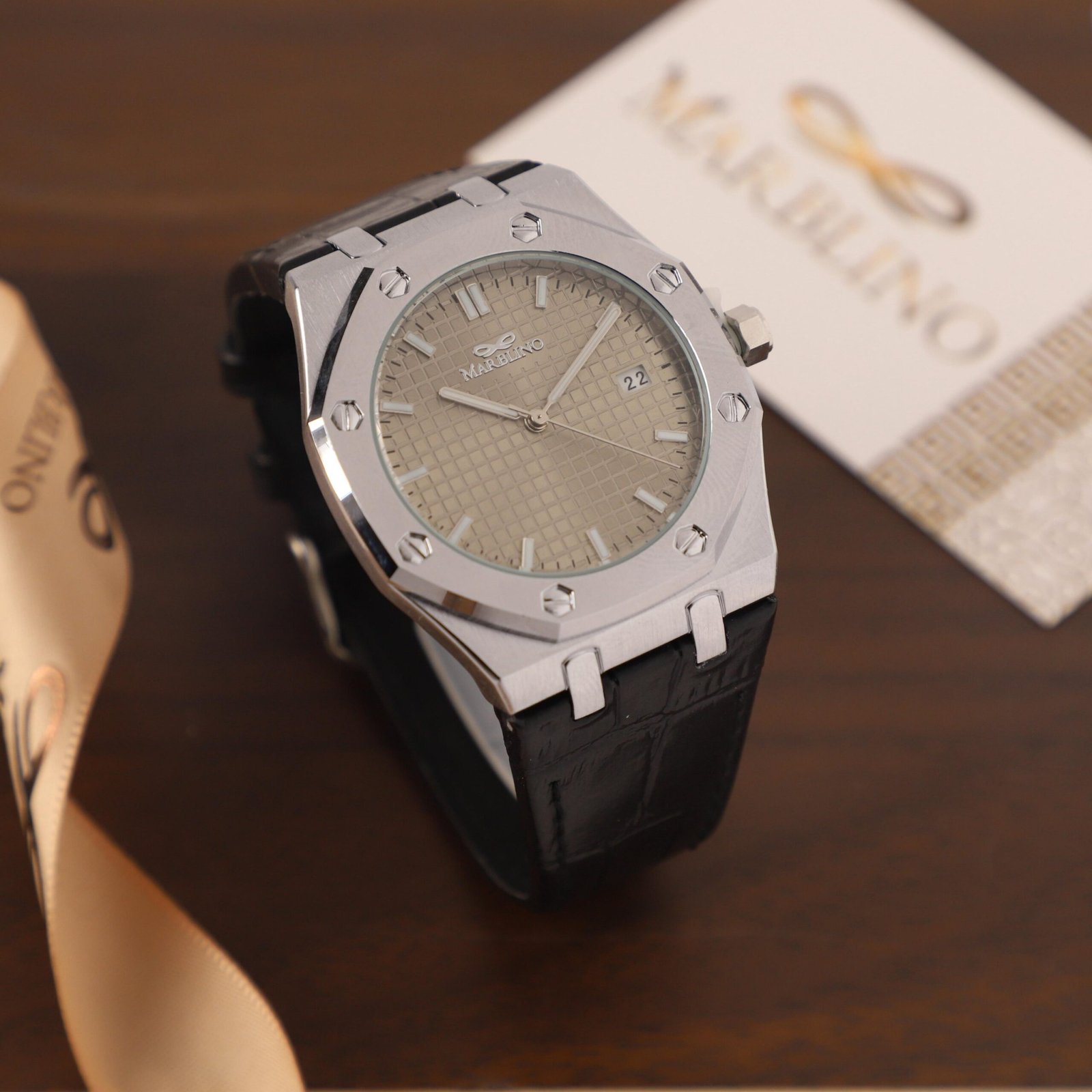 ​ساعة يد ماربلينو (Marbilino) رجالية فضية مثمنة، مينا بيج بنقشة مربعات وسوار جلد تمساح أسود.