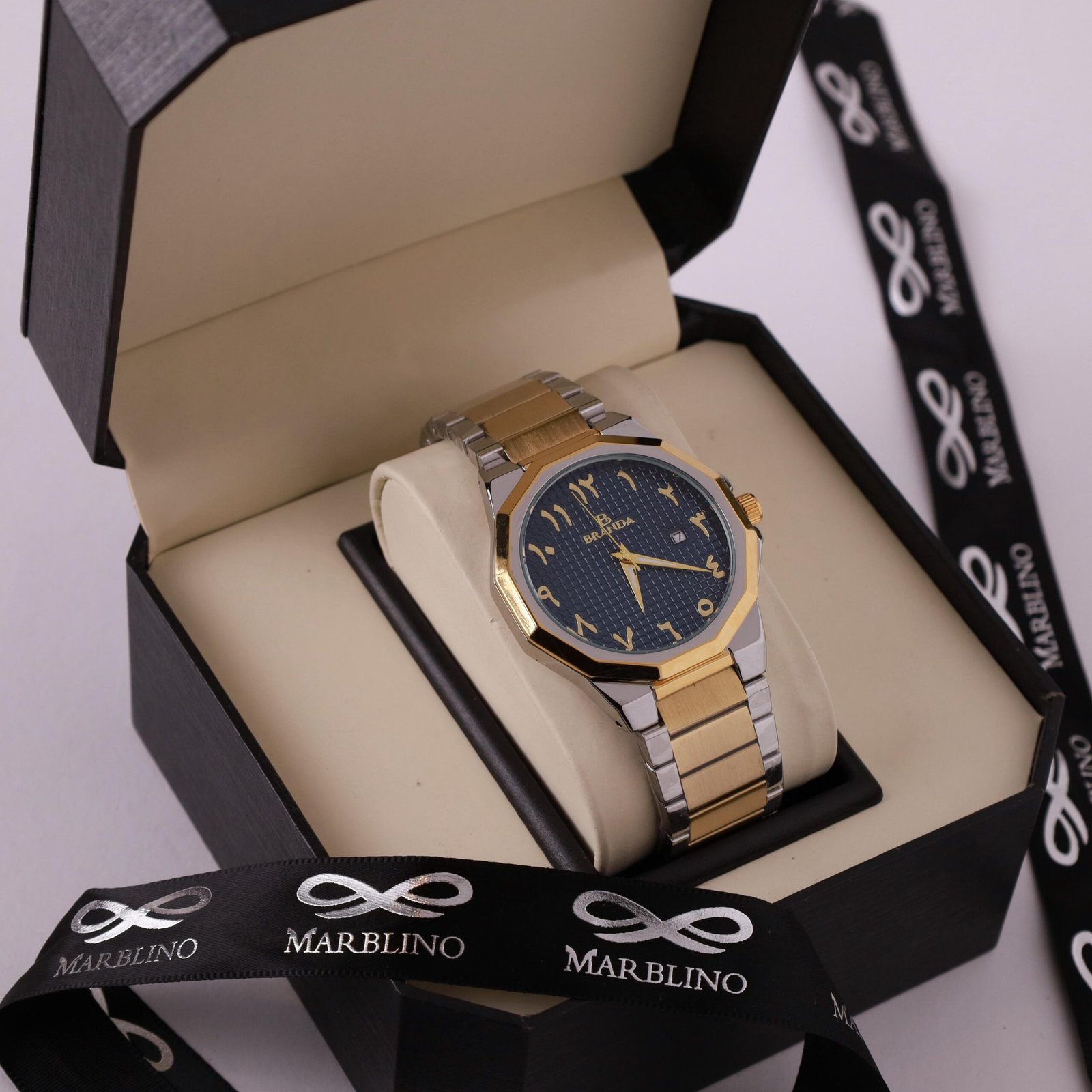 ساعة يد رجالية ثنائية اللون (ذهبي وفضي) من علامة BEATIGA بأرقام عربية شرقية، معروضة داخل علبة هدايا سوداء أنيقة ومحاطة بشريط ماربلينو (MARBLINO).