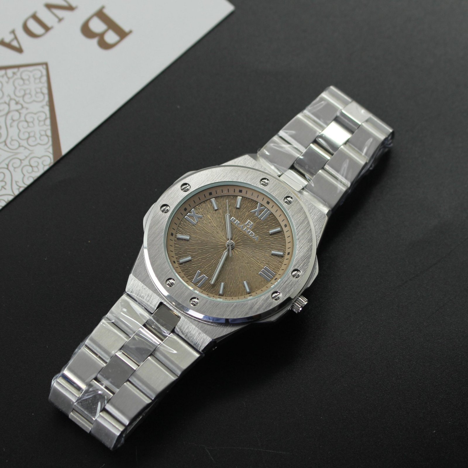 ​ساعة يد "BRAIDA" رياضية فاخرة، بهيكل مثمّن فضي، سوار ستانلس ستيل مدمج، وميناء بلون برونزي ونقش بارز (Tapisserie) وأرقام رومانية.