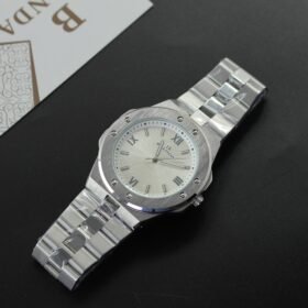 ساعة يد فضية كاجوال/رياضية أنيقة، تصميم أيقوني بإطار مثبّت بمسامير، بسوار معدني ووجه منقوش، تحمل شعار "BH BANDA".