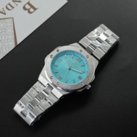 "ساعة يد (رجالية/للجنسين) بتصميم مثمن الأضلاع رياضية-فاخرة، بحافظة وسوار من الفولاذ المقاوم للصدأ فضي اللون، ومينا باللون الأزرق الفيروزي (Tiffany Blue) بنمط مزخرف، وعلامة تجارية BRAIDA."